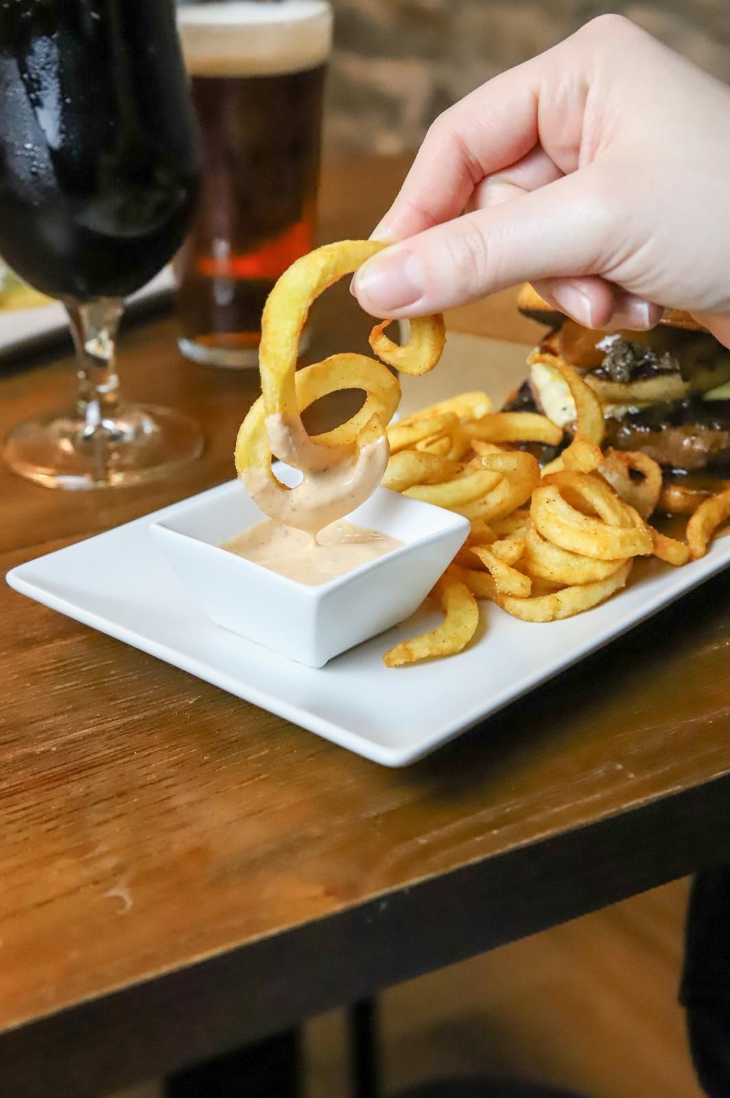 Una persona está mojando patatas fritas en salsa en un plato.