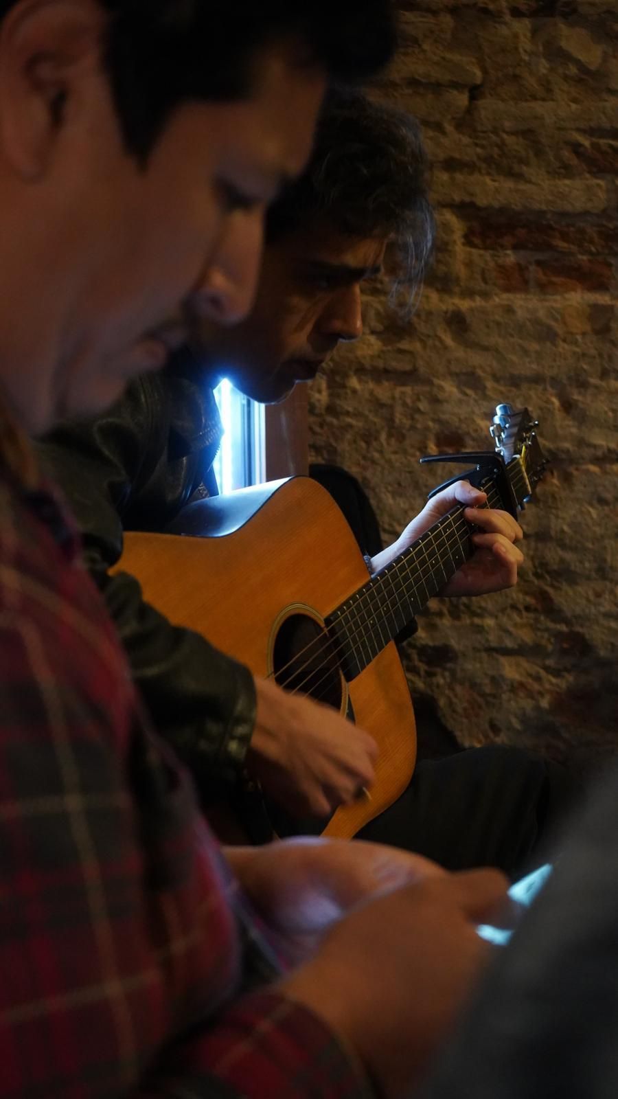 Dos hombres tocan guitarras y miran sus teléfonos.