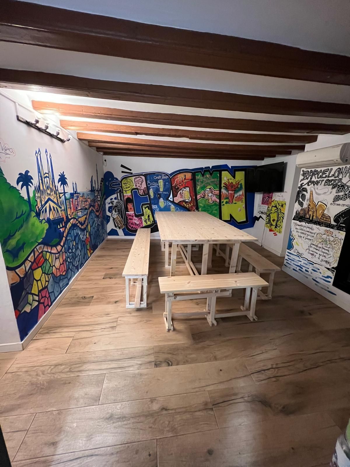 Una habitación con una mesa y bancos y grafitis en las paredes.