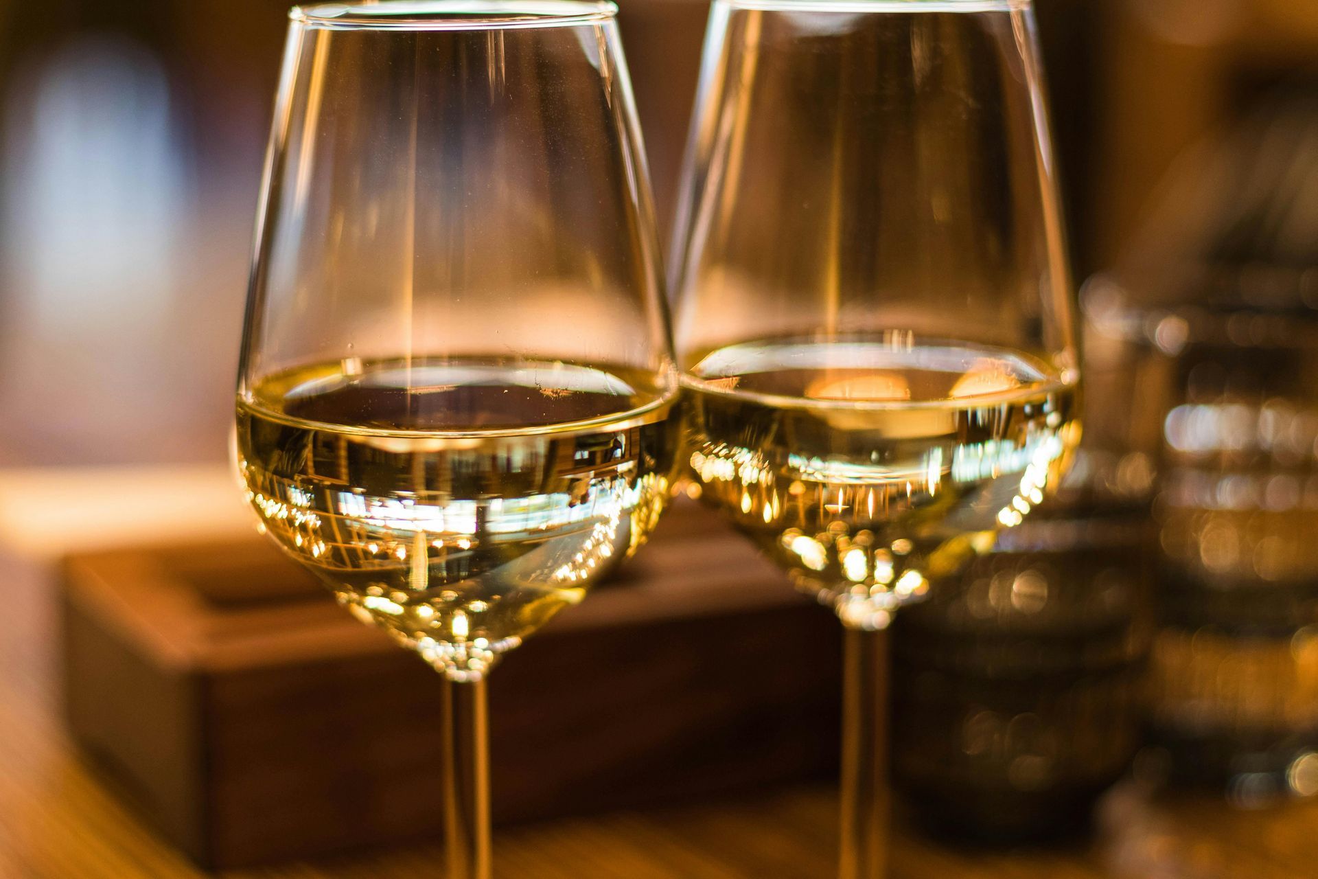 Dos copas de vino blanco están sentadas sobre una mesa de madera.