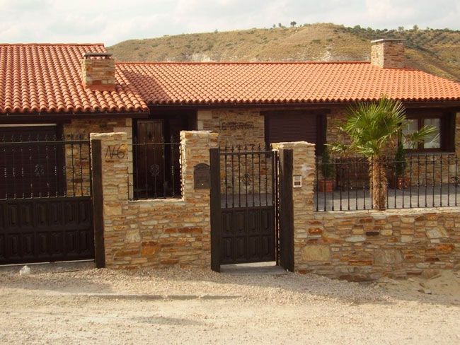 Una casa con techo de tejas rojas y pared de piedra