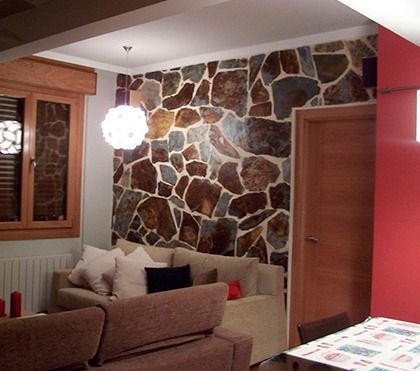 Una sala de estar con una pared de piedra y un sofá.