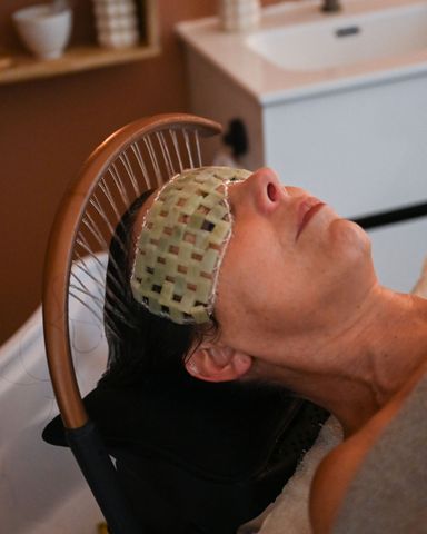 Une personne allongée dans un fauteuil, un masque pour les yeux en gel sur la tête, dans un décor digne d'un spa.