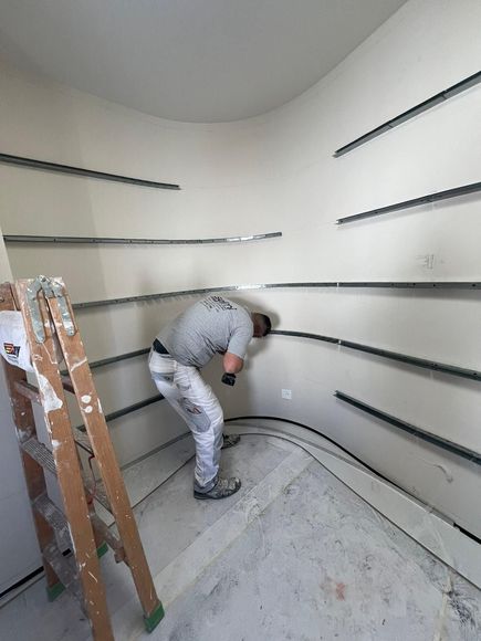 Un homme est à genoux et peint un mur avec un rouleau.