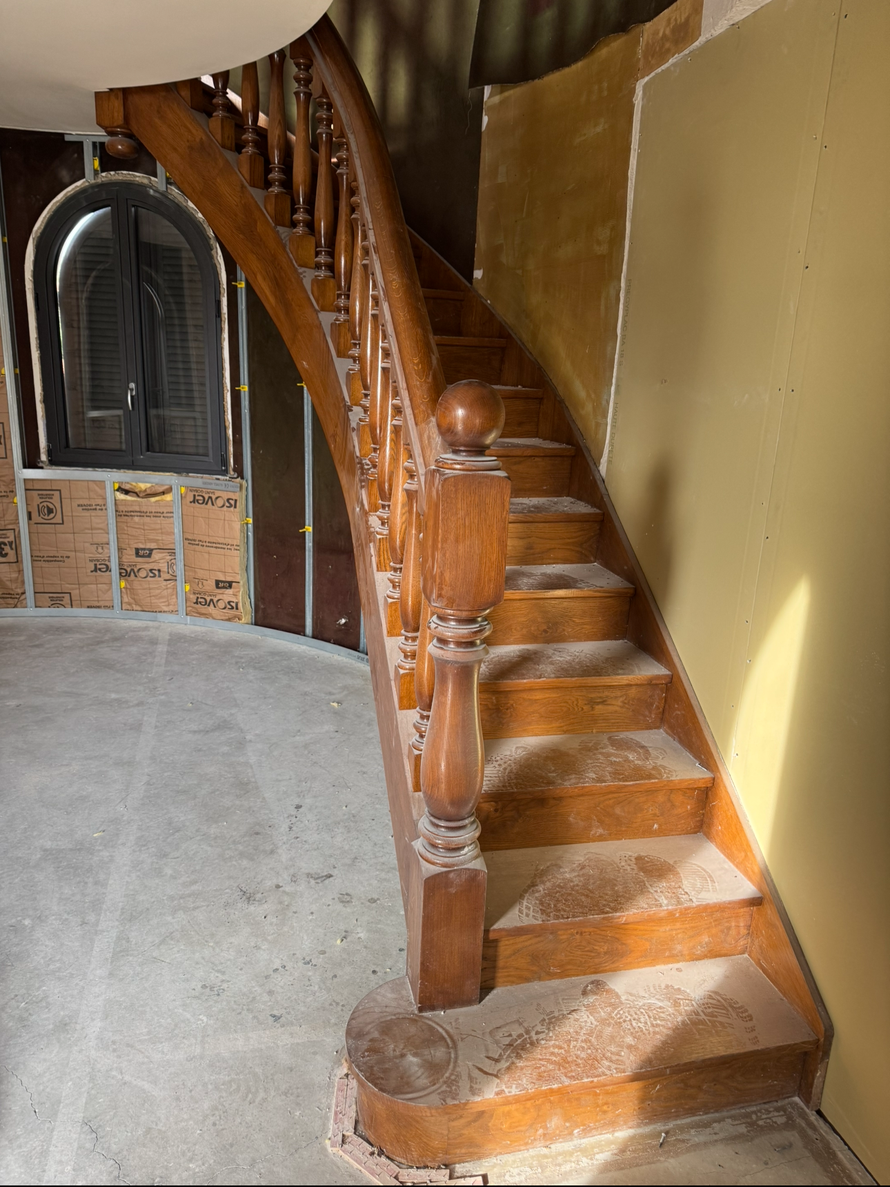 Escalier en bois incurvé dans un bâtiment en rénovation.