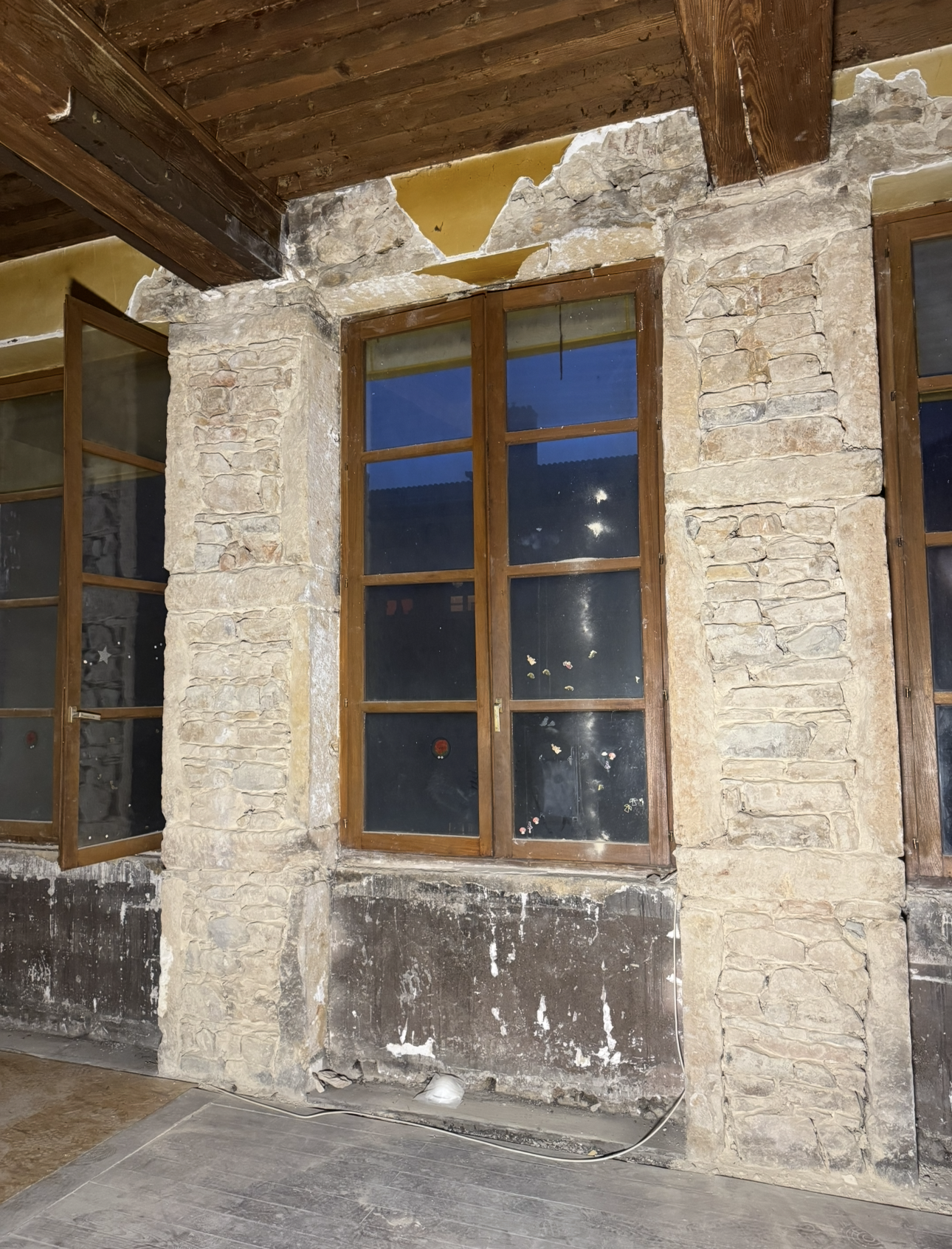 Façade d'un bâtiment en pierre avec fenêtres et poutres en bois.