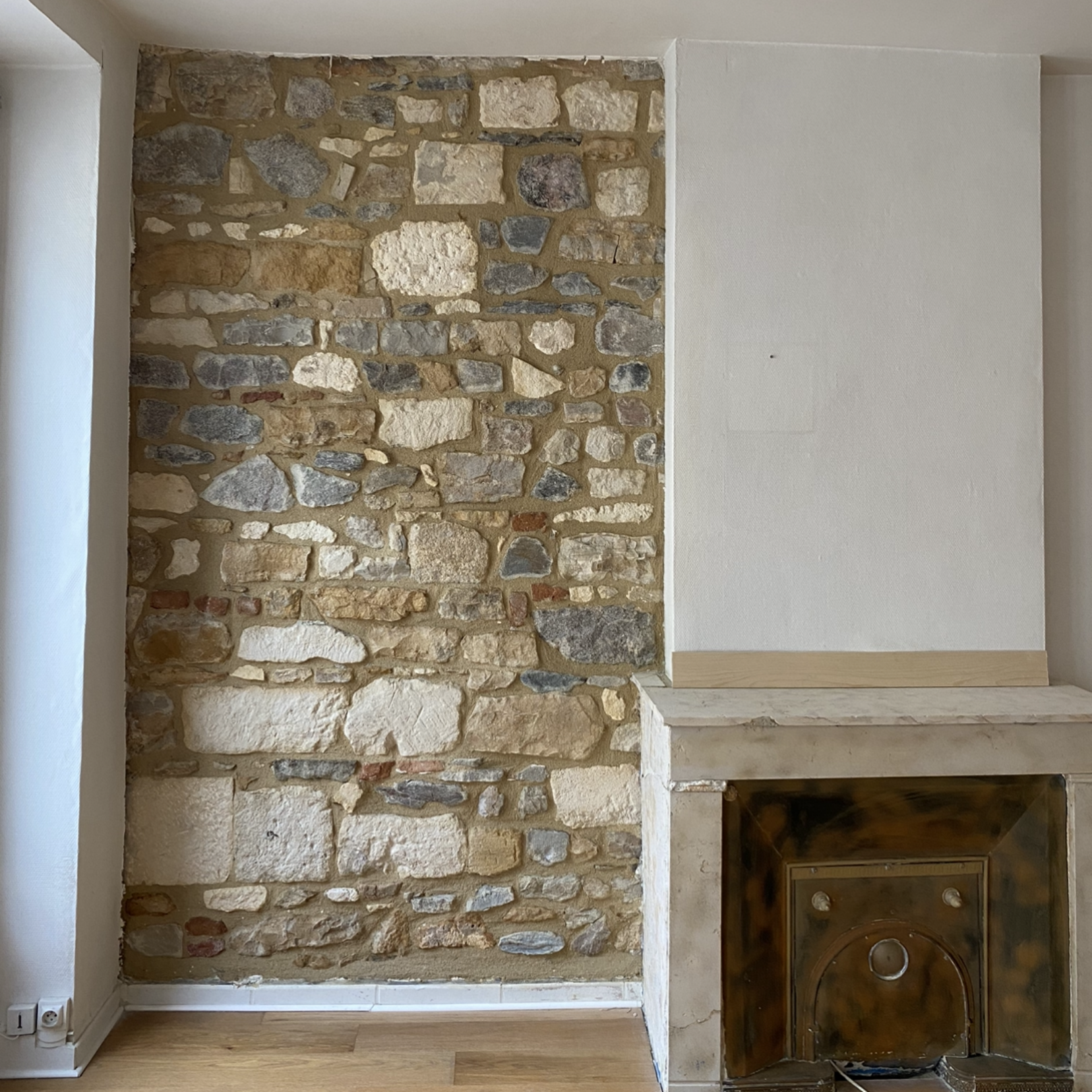 Mur en pierre et cheminée, un côté peint en blanc.