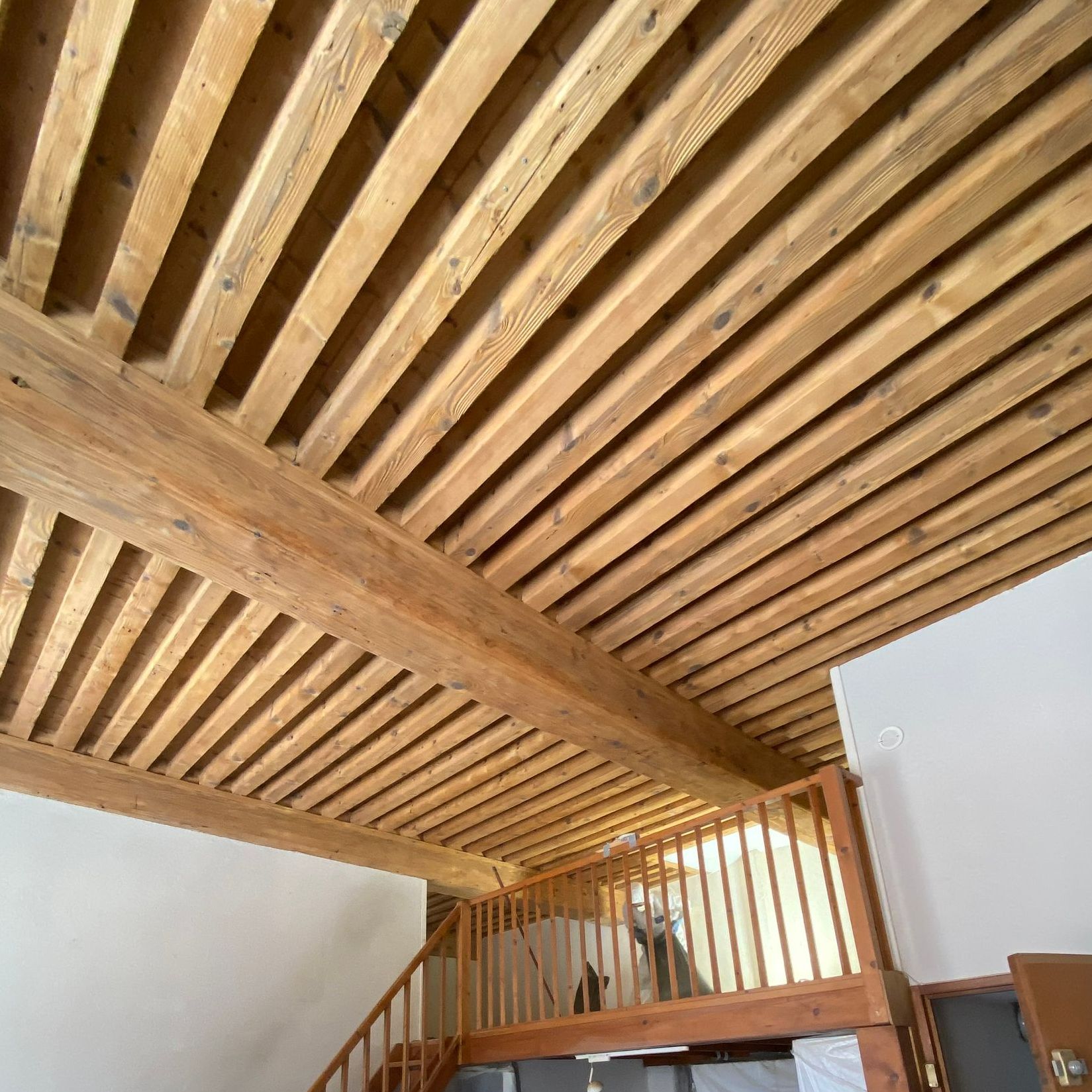 Plafond à poutres apparentes en bois avec cage d'escalier et rampe.