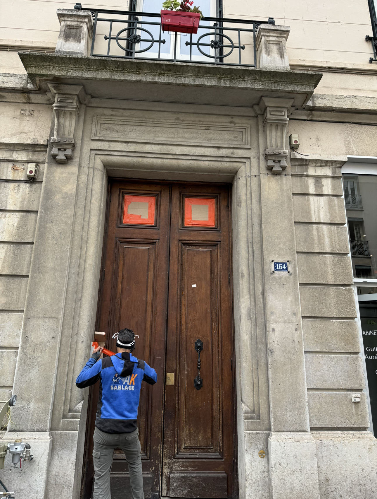 Avant sablage d'une porte en bois d'un bâtiment à façade en pierre.