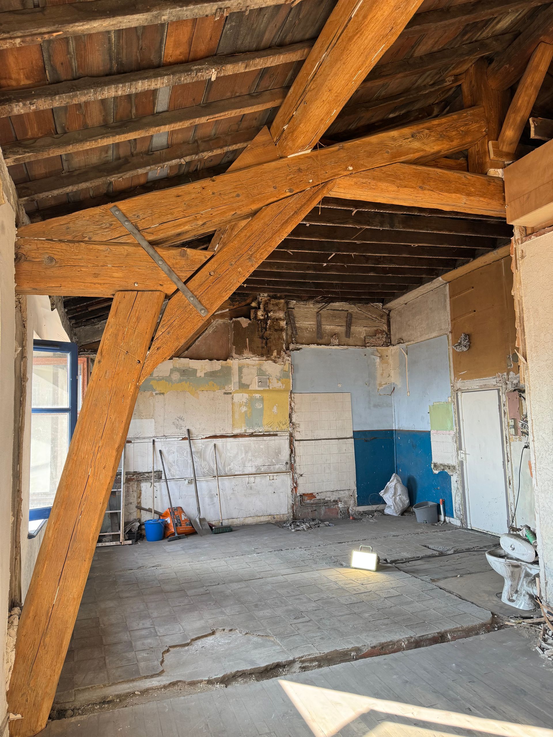 Intérieur en cours de rénovation avec poutres en bois apparentes décapées.