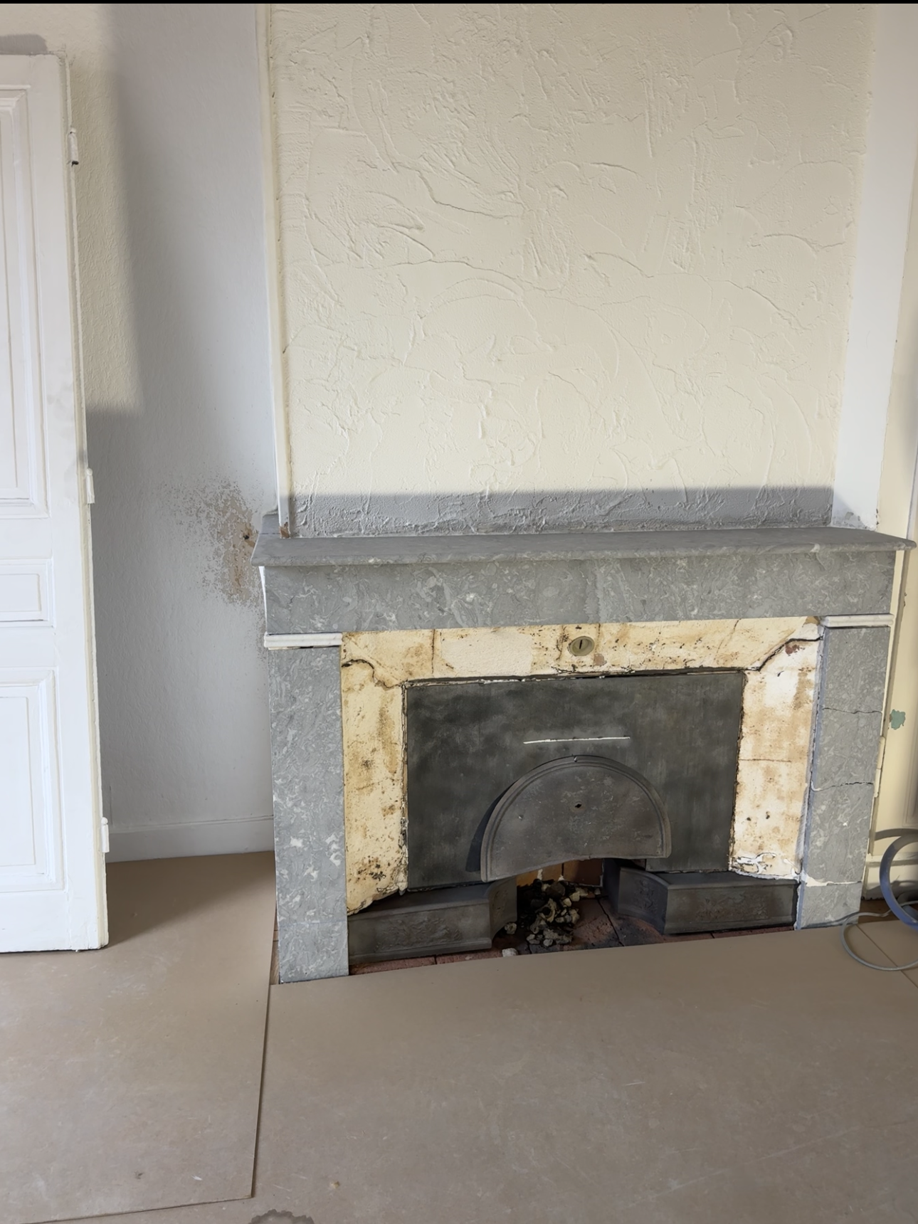 Cheminée avec un manteau en pierre dans une pièce aux murs et au sol clairs.