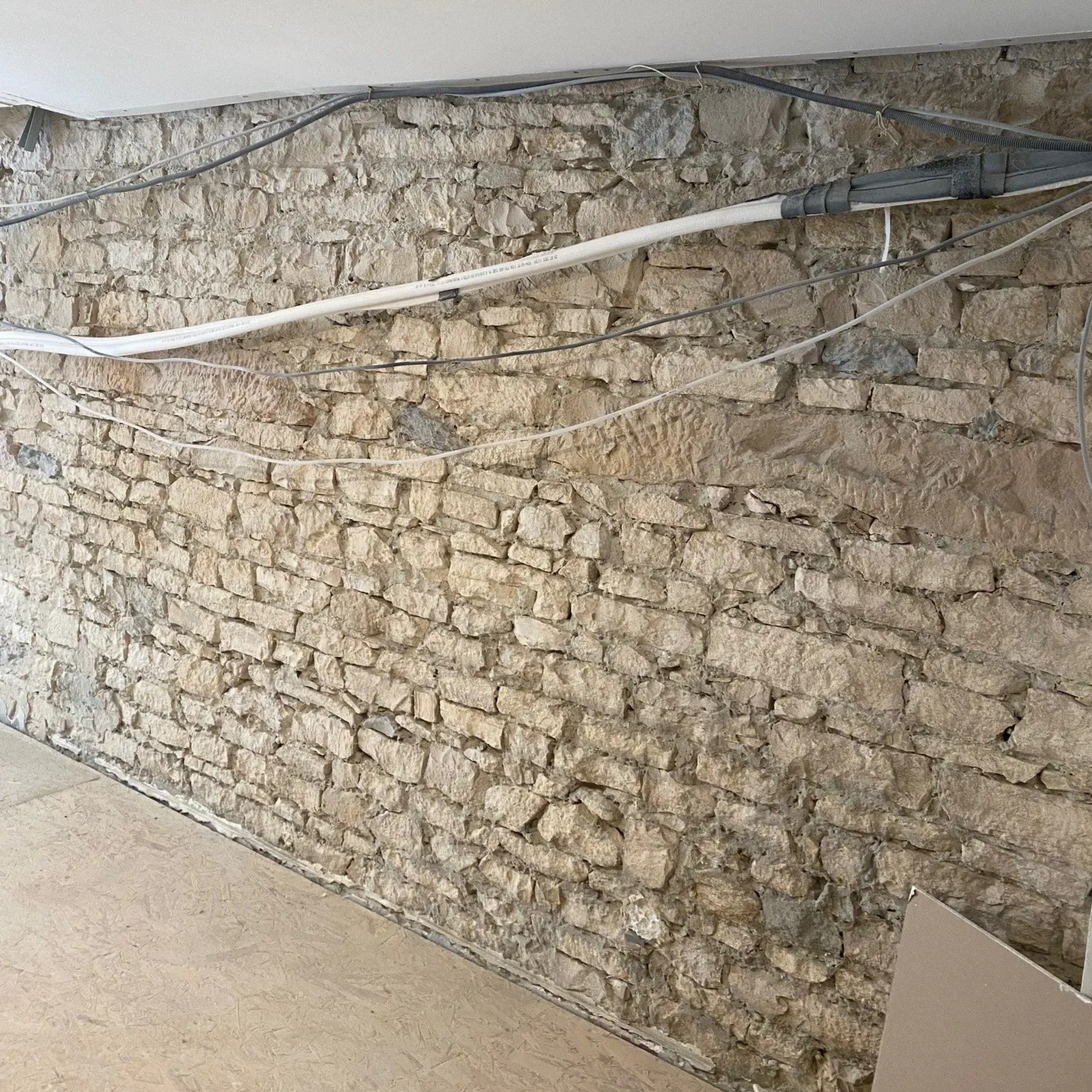 Mur de briques en pierre avec conduit et câblage le long du haut.