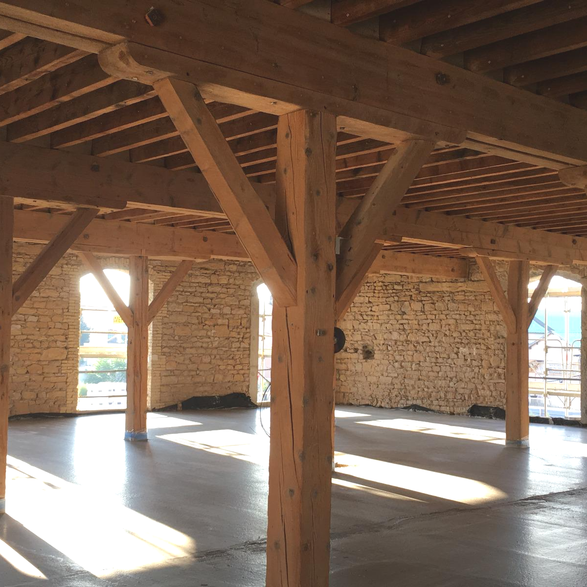 Intérieur d'un bâtiment à ossature bois avec la lumière du soleil traversant les fenêtres.