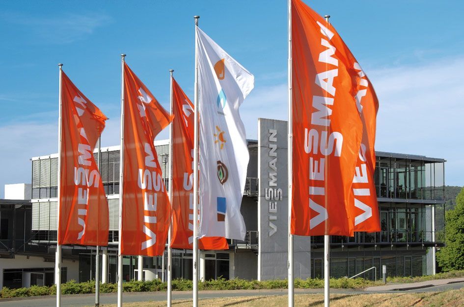 Orange und weiße Flaggen wehen vor einem modernen Glasgebäude an einem sonnigen Tag