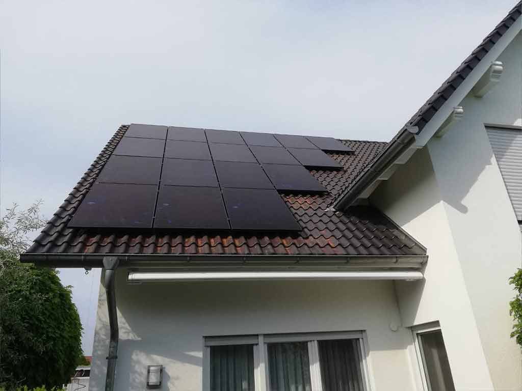 Ein weißes Haus mit Sonnenkollektoren auf dem Dach.