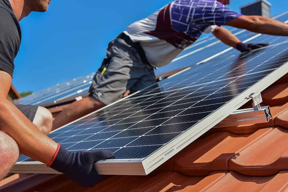 Zwei Männer installieren Solarmodule auf einem Dach.
