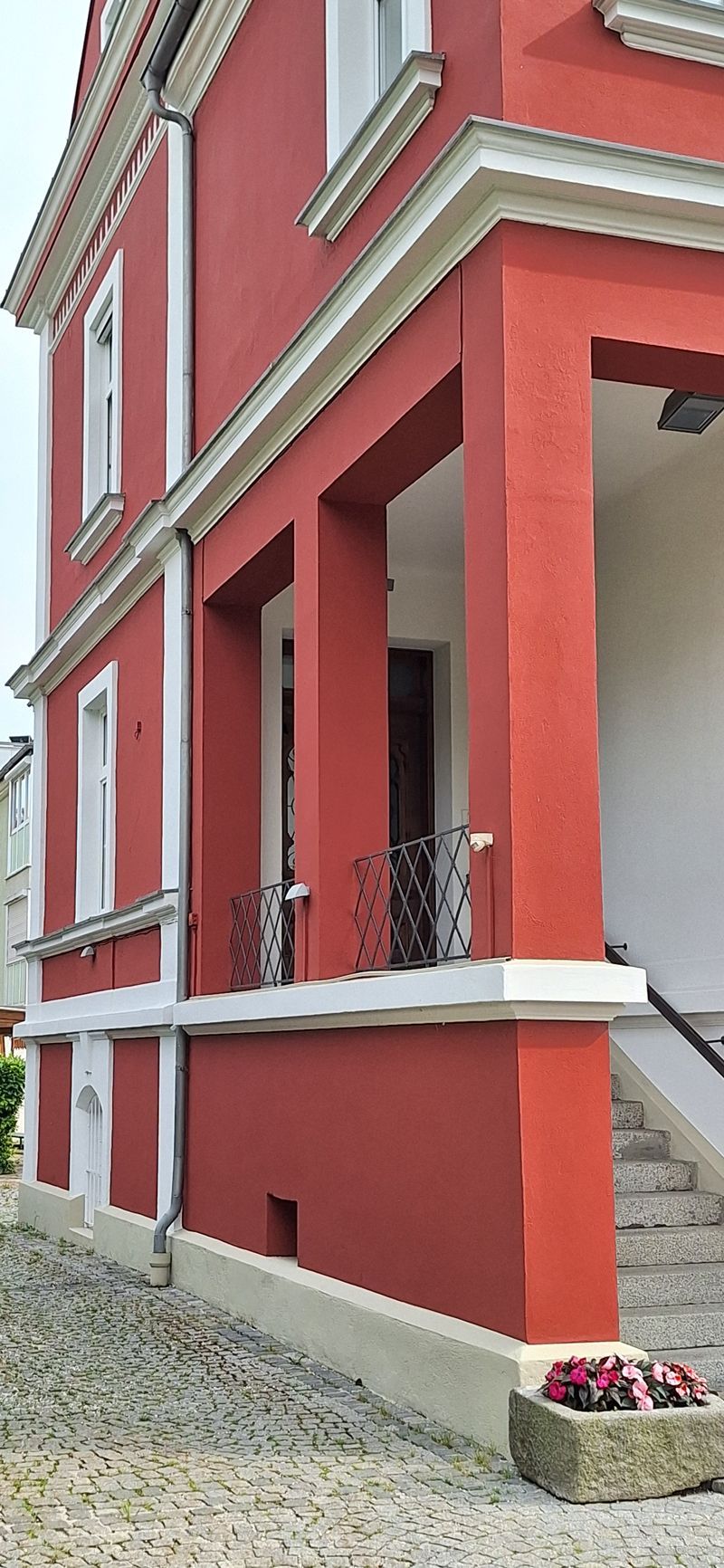 Ein rot-weißes Gebäude mit einer Veranda und einer Treppe.