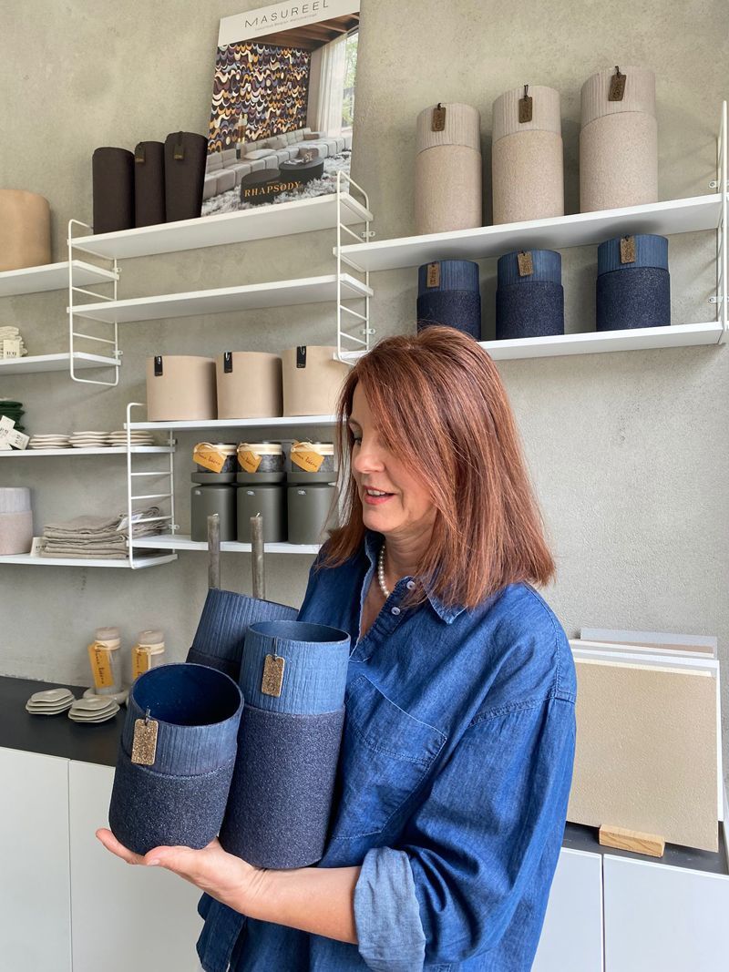 Eine Frau hält in einer Küche drei Körbe in ihren Händen.