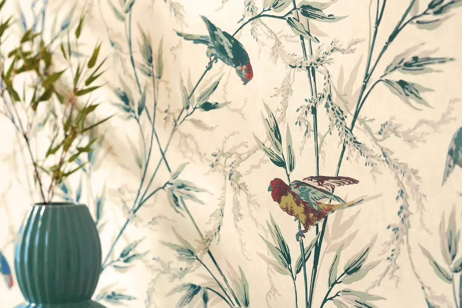 Auf einem Tisch vor einer Wand steht eine Vase mit Blumen, darauf Vögel und Blätter.