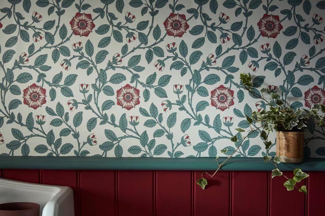 Ein Zimmer mit einer Blumentapete und einer Topfpflanze an der Wand.