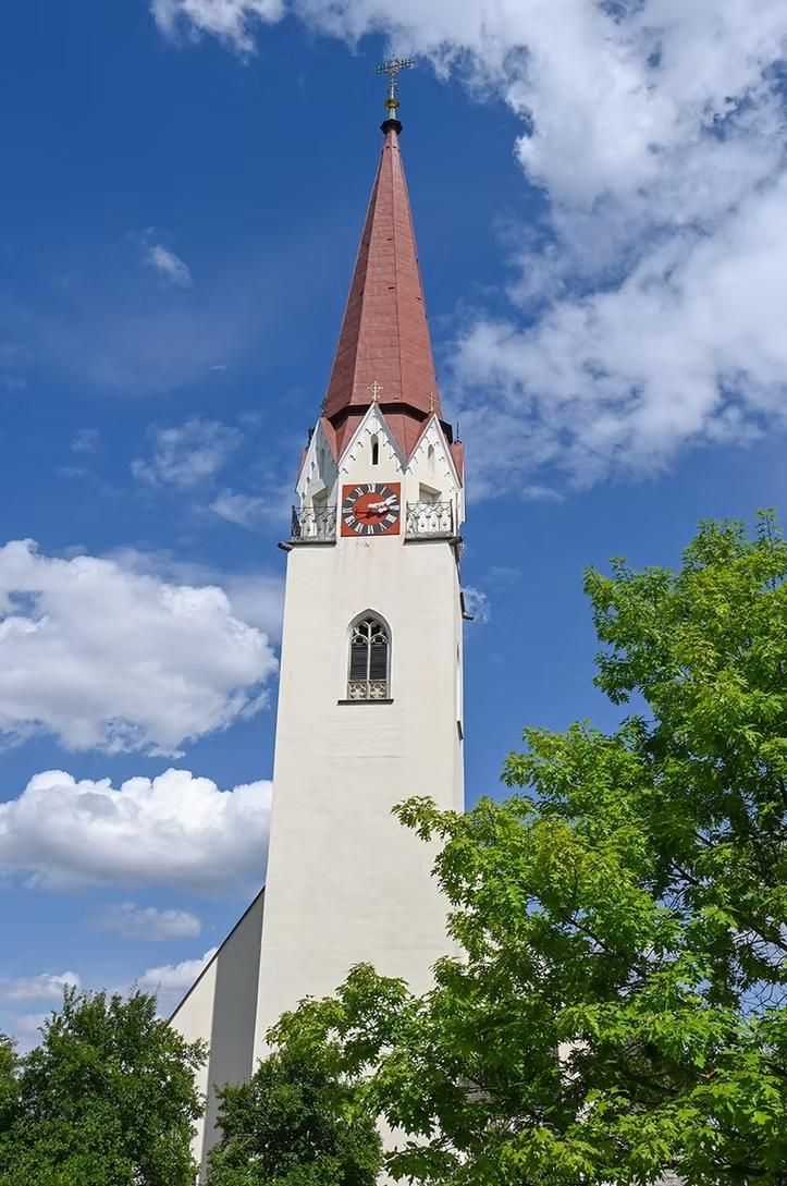 Eine weiße Kirche mit einem roten Kirchturm und einer Uhr darauf