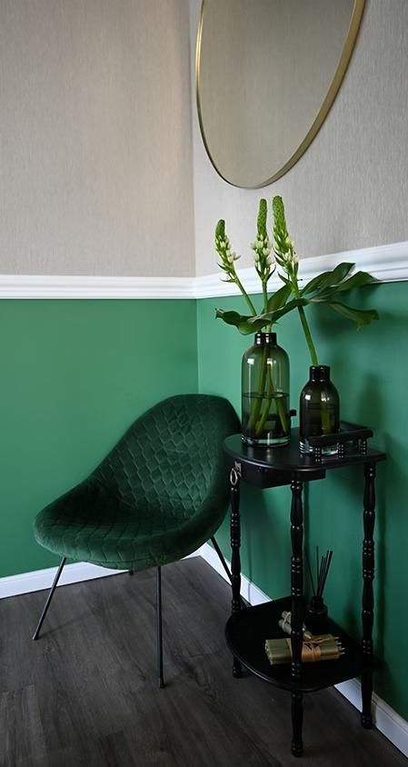 Ein grüner Stuhl steht neben einem kleinen Tisch mit einer Vase mit Blumen darauf.