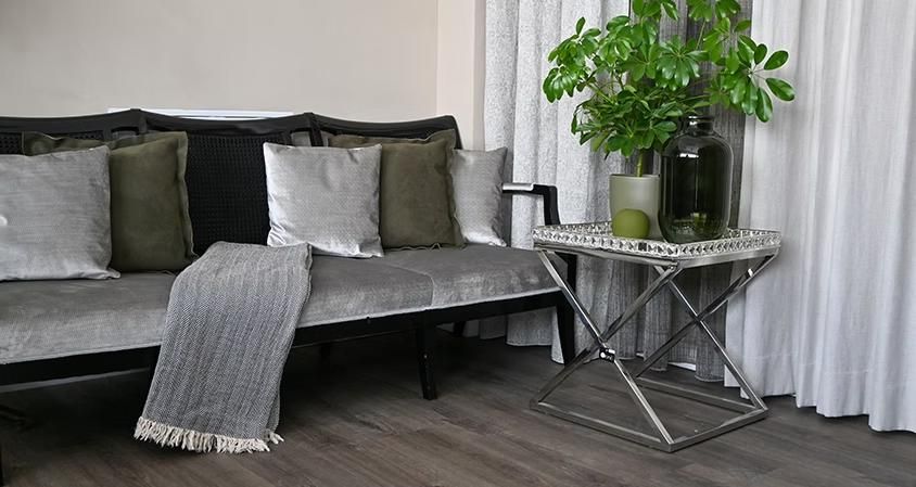 Ein Wohnzimmer mit Sofa, Tisch und Topfpflanze.