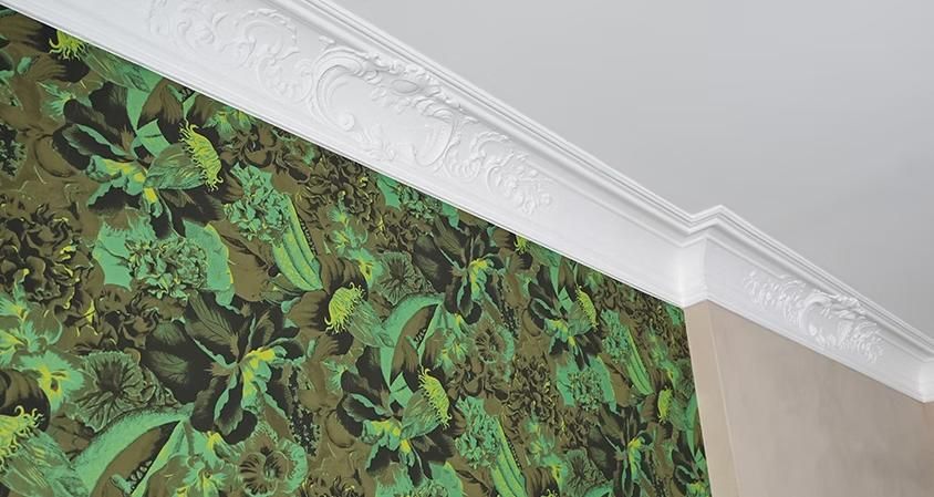 Ein Raum mit grüner Tapete und einem weißen Gesims an der Decke.
