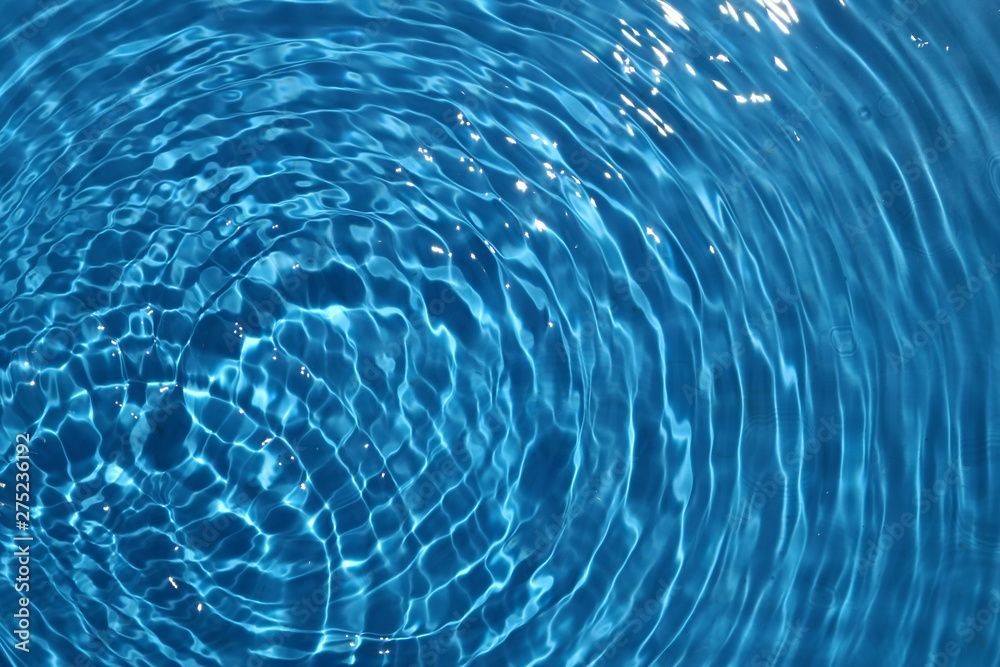 Konzentrische blaue Wasserwellen mit Sonnenreflexionen.