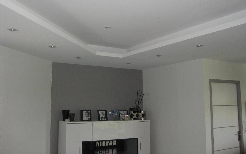 Salon moderne avec plafond blanc, mur d’accent gris, cheminée et photos encadrées sur le manteau de la cheminée