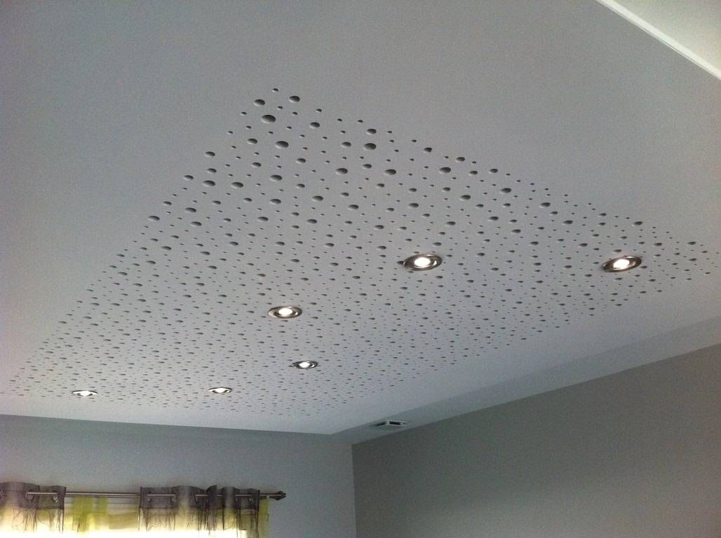 Plafond parsemé de points évoquant des étoiles et de trois spots encastrés au-dessus d’une fenêtre de la pièce