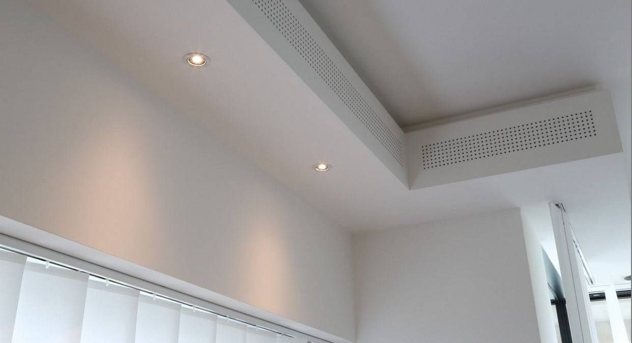 Plafond blanc avec des spots encastrés et une retombée de plafond