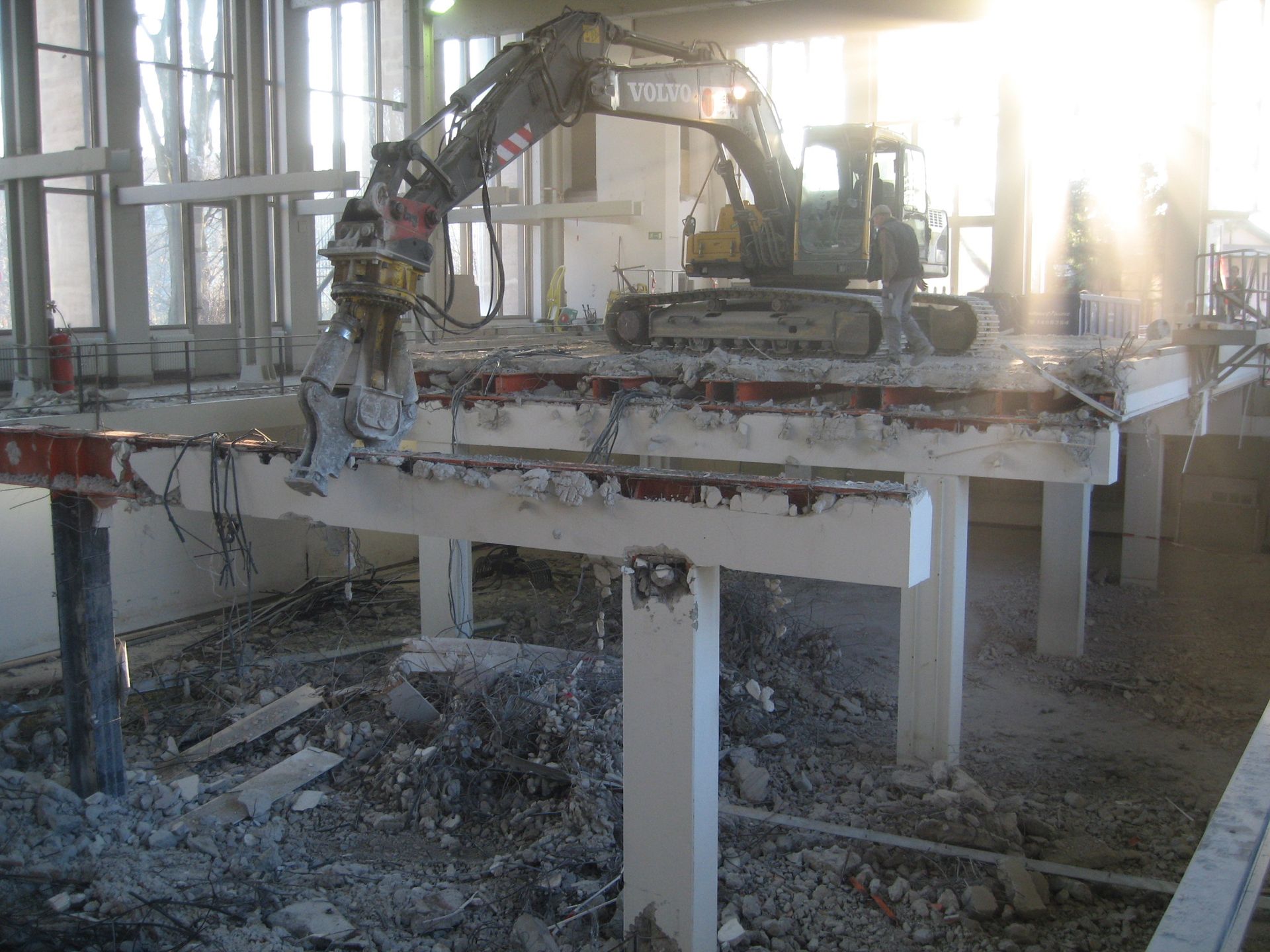 Ein Bagger mit Betonbeißer bei Abrissarbeiten auf einer Hochebene im Gebäudeinneren.