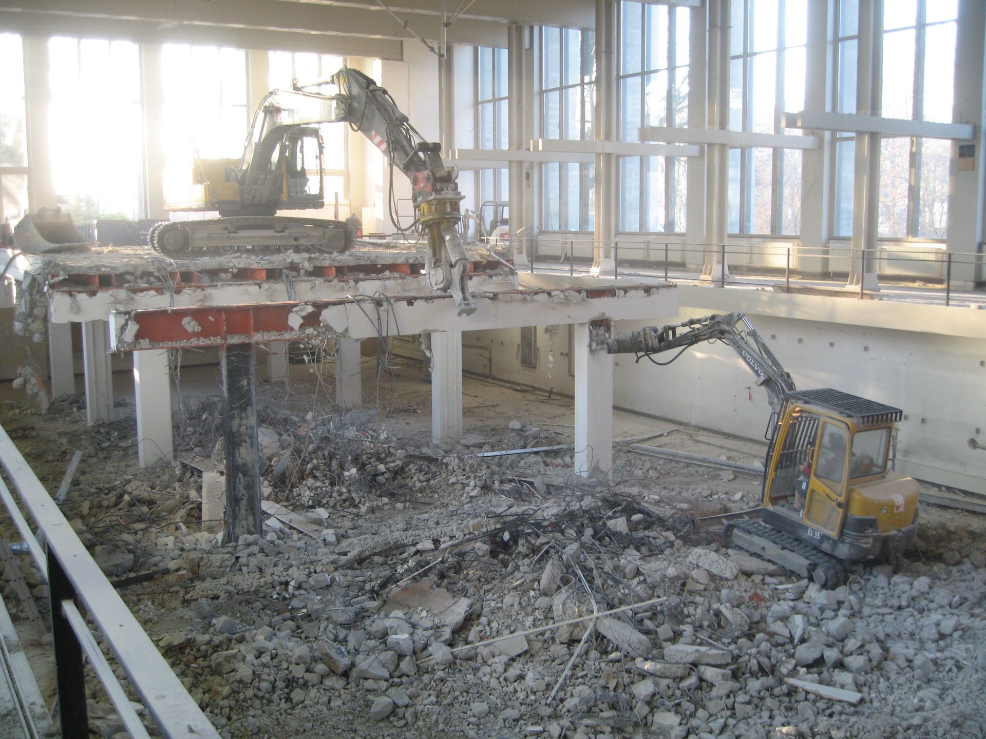 Innenabbruch einer Industriehalle mit zwei Baggern auf unterschiedlichen Ebenen.