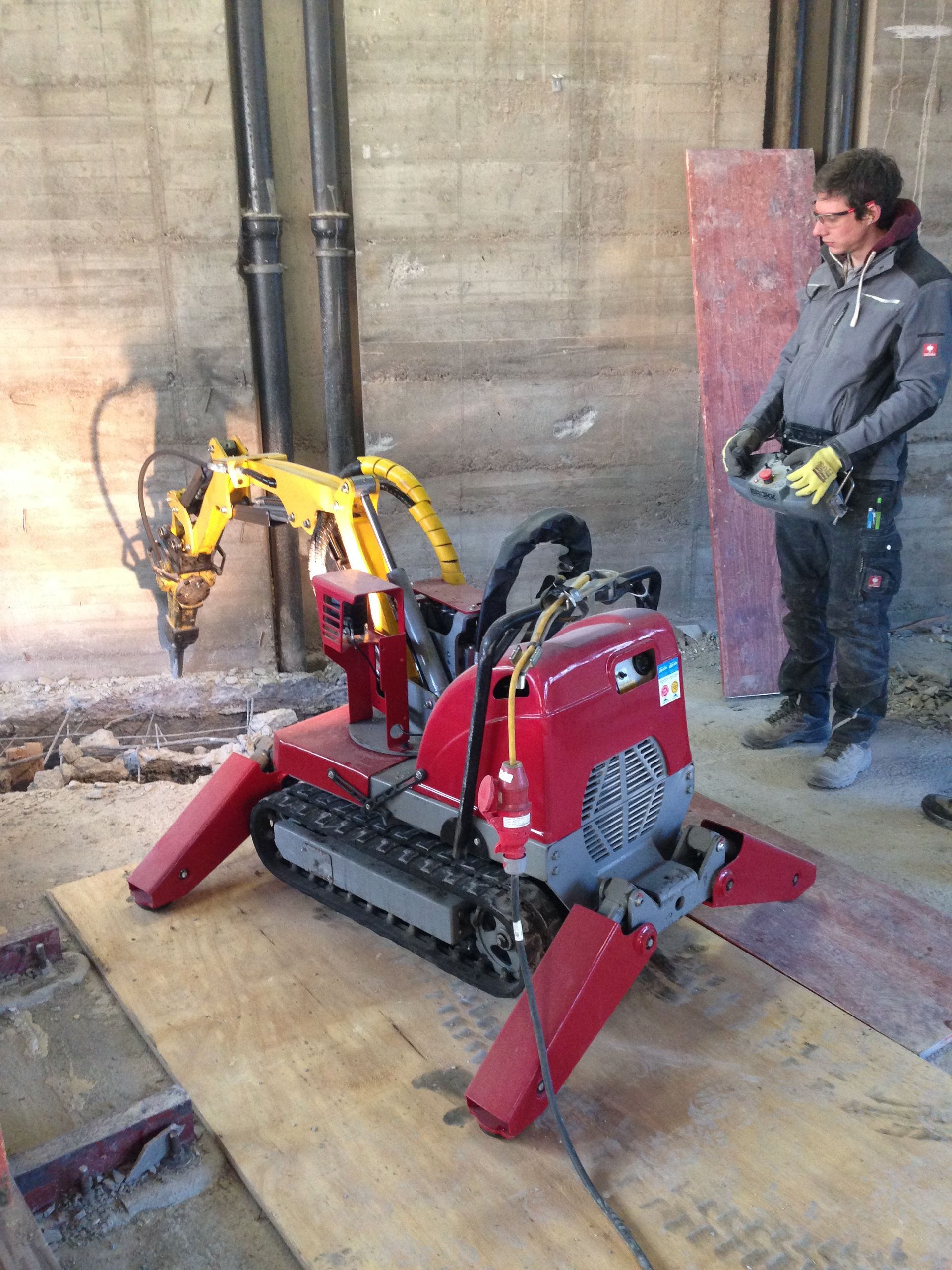 Ein ferngesteuerter Abbruchroboter mit Meißelhammer bei Stemmarbeiten an einer Betonwand.