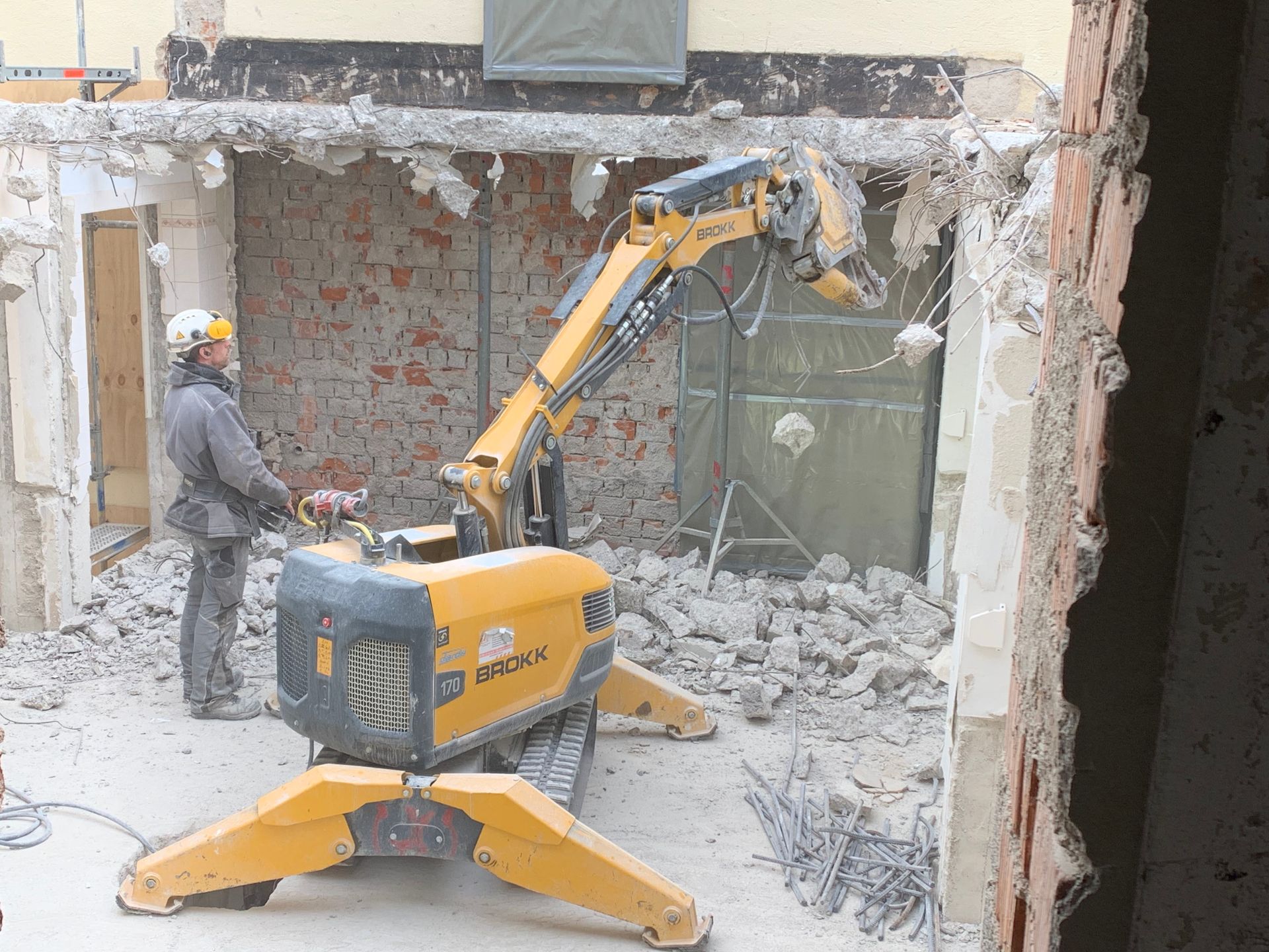 Ein Arbeiter steuert einen emissionsfreien Elektro-Abbruchroboter bei Abrissarbeiten im Innenraum.