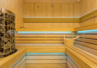 Drewniana sauna z wiadrem i piecem.