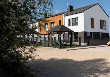 Biały dom z altaną przed nim.