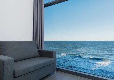 Salon z kanapą i dużym oknem z widokiem na ocean.