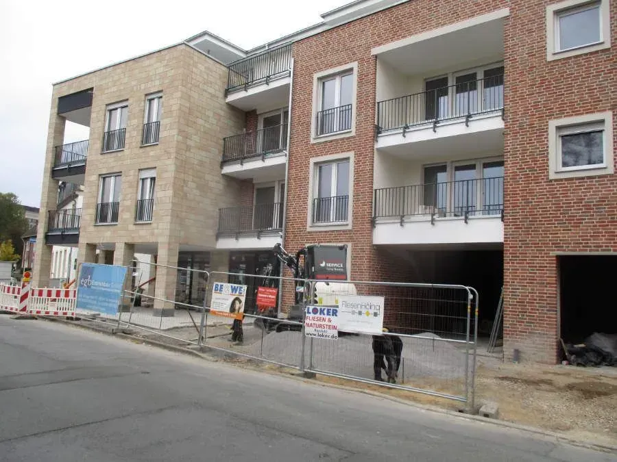 ein riesiges Backsteingebäude mit einem Zaun davor