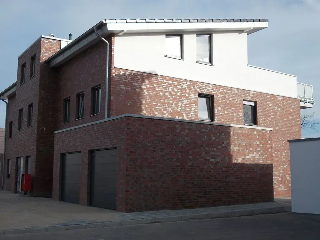 ein Backsteingebäude mit zwei Garagen und einem Balkon