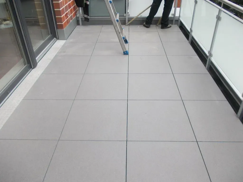 ein Mann steht auf einem Balkon mit einer Leiter und einem Besen