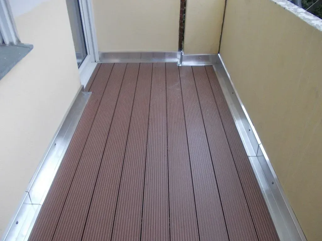 ein brauner Holzboden auf einem Balkon neben einer gelben Wand