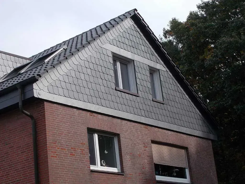 ein Backsteinhaus mit zwei Fenstern und einem Dach