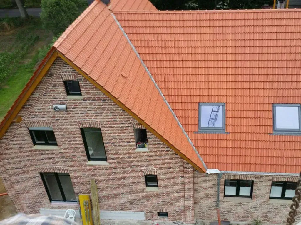 ein Backsteingebäude mit einem roten Dach und zwei Fenstern