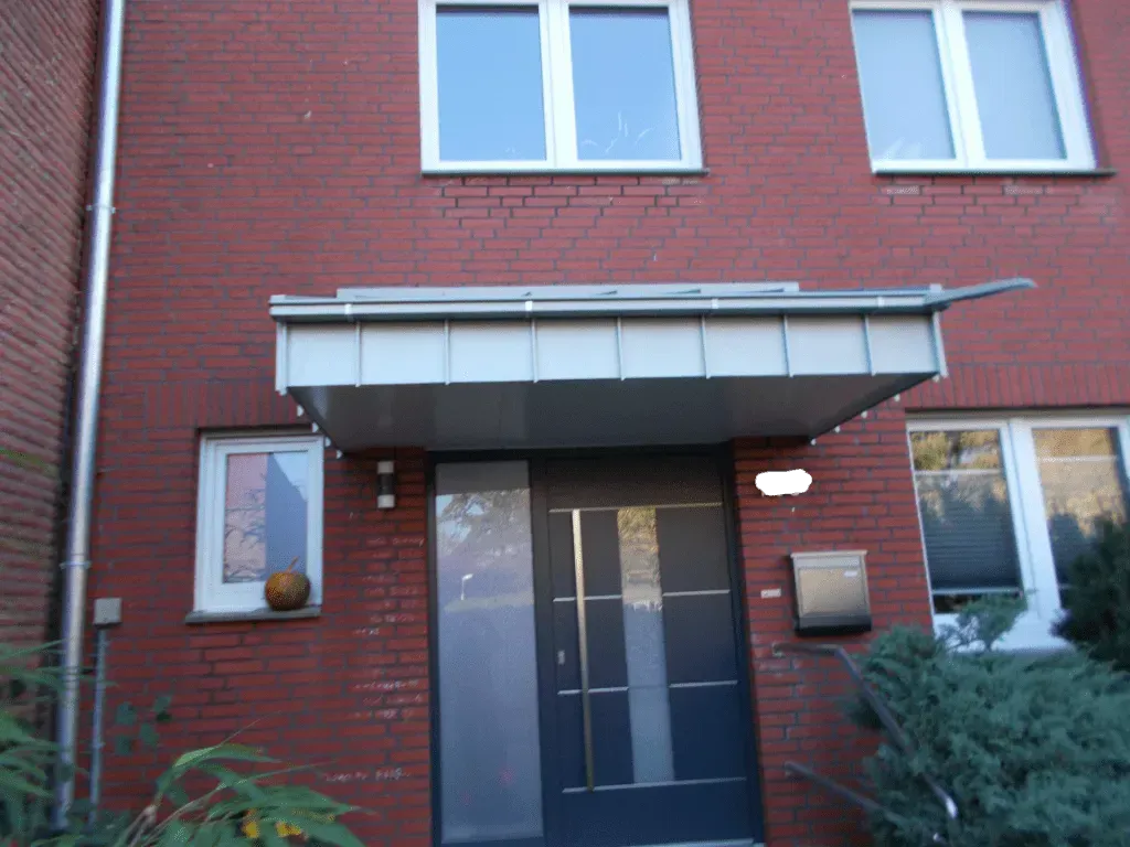 eine rote Backsteinmauer mit einer schwarzen Haustür und einem weißen Fenster