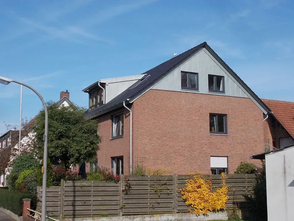 ein Backsteinhaus mit einem Holzzaun davor