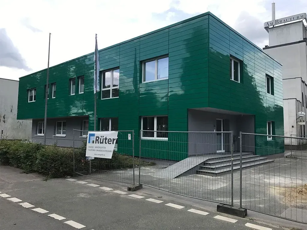 ein grünes Gebäude mit einem Schild davor