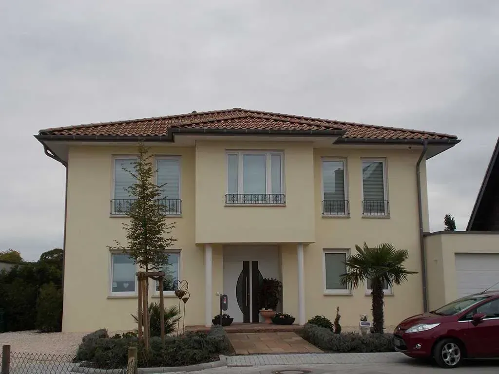 ein rotes Auto ist vor einem gelben Haus geparkt