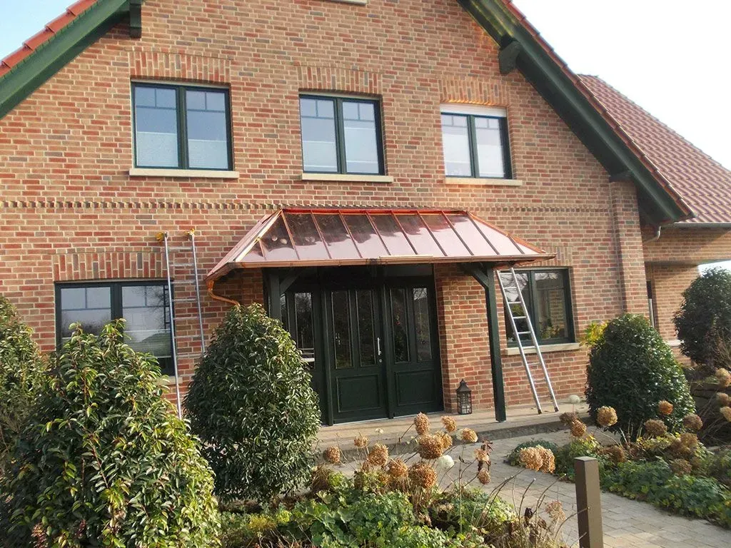 ein Backsteinhaus mit einer grünen Tür und zwei Fenstern